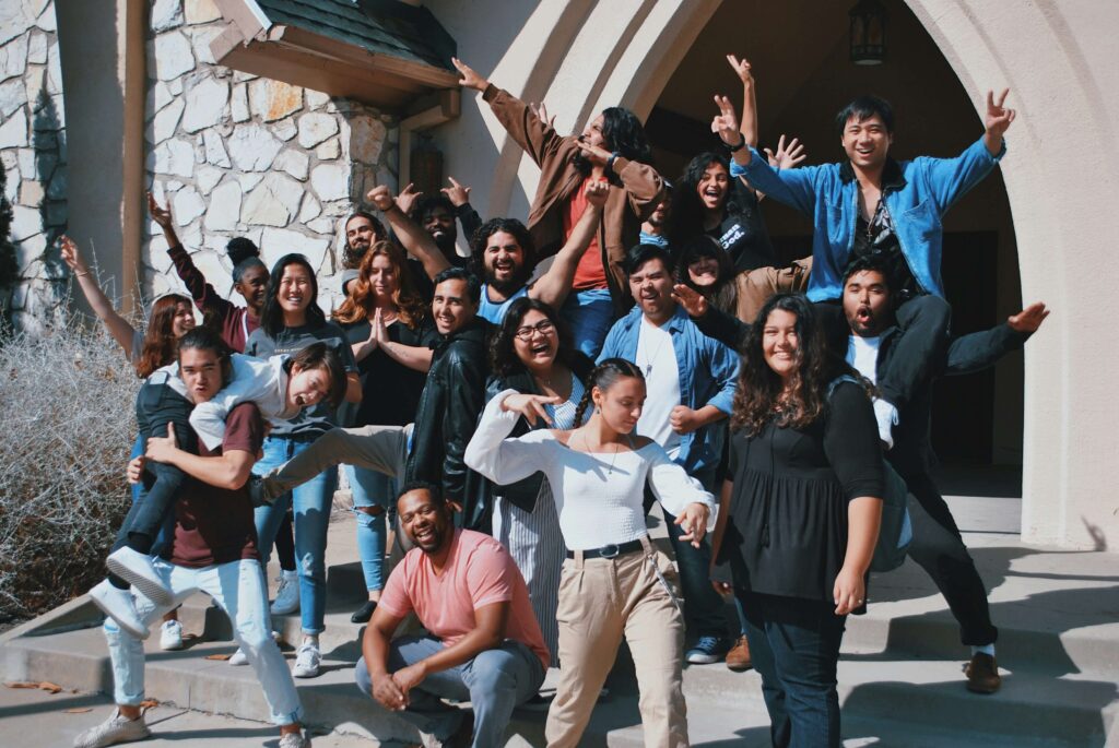 A group of people are posing enthusisastically in fron of an archway.